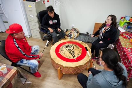 four people around a pow wow drum